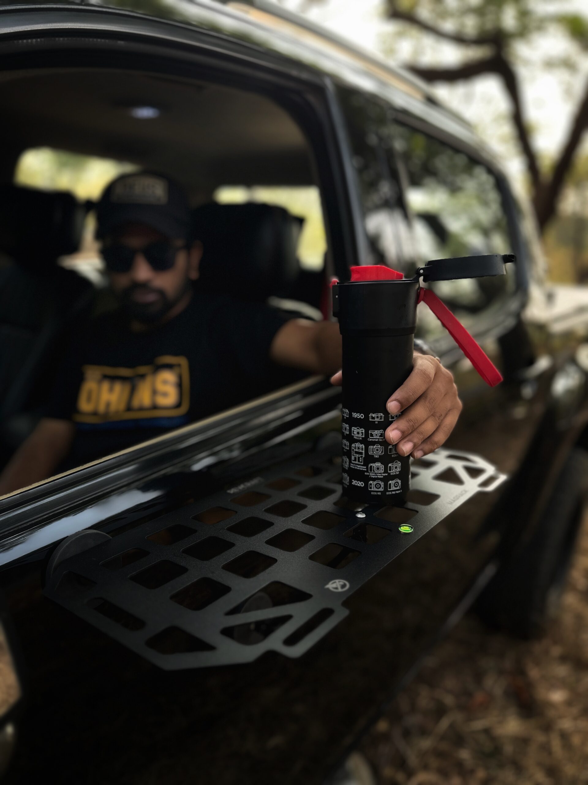 RevCraft MagRack magnetic outdoor tray mounted on a 4x4 steel surface, close-up of three rubber coated magnets on MagRack tray, RevCraft MagRack tray showing embedded spirit level, MagRack outdoor tray with cross bar support for stability, MagRack tray holding coffee cups and snacks during camping, RevCraft MagRack used as a cooking prep tray at an overlanding campsite, MagRack tray mounted on a 4x4 body panel during a roadside stop, RevCraft MagRack powder coated steel tray product close-up, MagRack tray load test with tools and gear, RevCraft MagRack tray packed inside protective carry bag, MagRack tray stored in vehicle trunk for travel, RevCraft MagRack magnetic tray mounted on a 4x4 tailgate, MagRack tray used for organizing recovery gear, RevCraft MagRack outdoor tray used for city dine-in setup, MagRack tray mounted on a steel roof rack side, close-up of MagRack cross bar and mounting structure, RevCraft MagRack tray holding camera gear safely, MagRack tray leveled using spirit level for hot drinks, RevCraft MagRack tray in overland setup with cookware, MagRack magnetic tray for 4x4 camping and outdoor use
